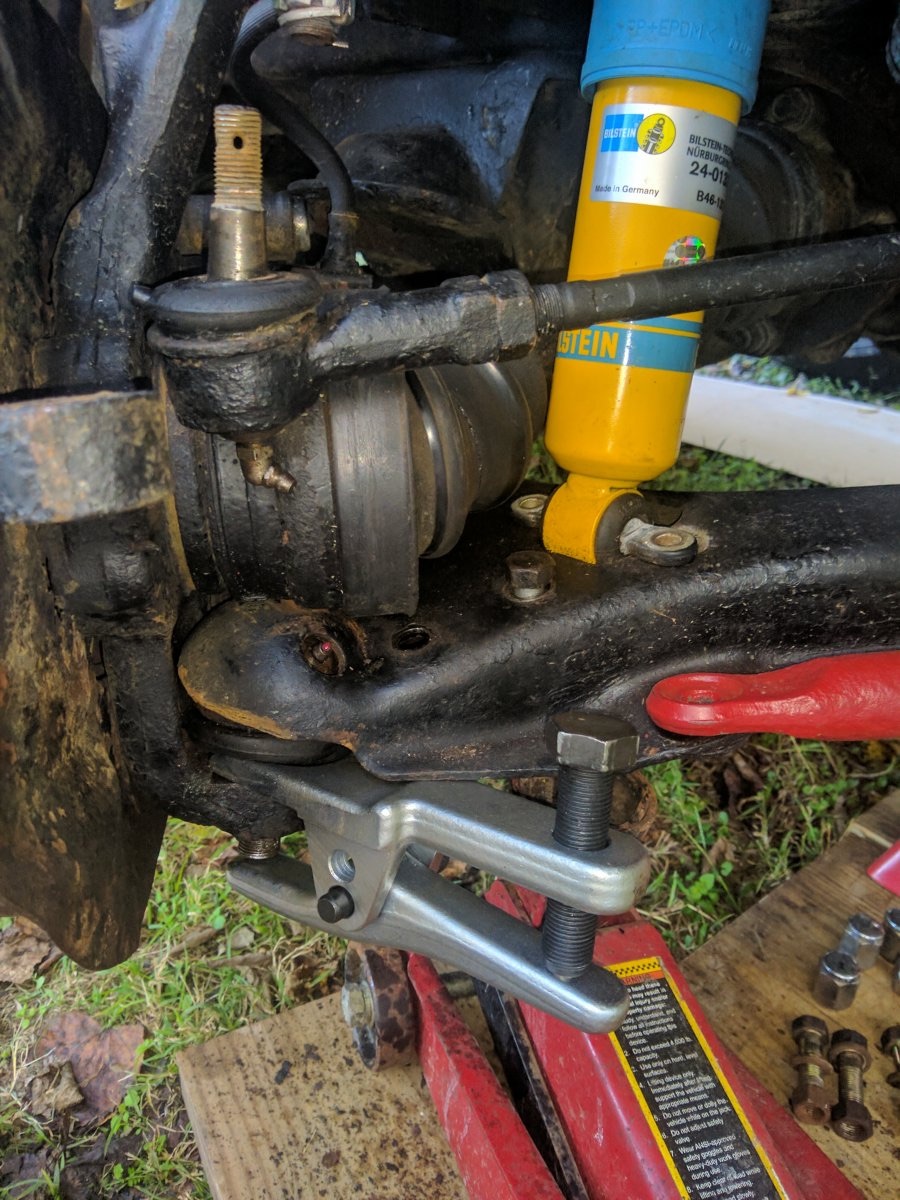 Ball joint separator clamped on at the correct angle, with the brake hose visibly taut