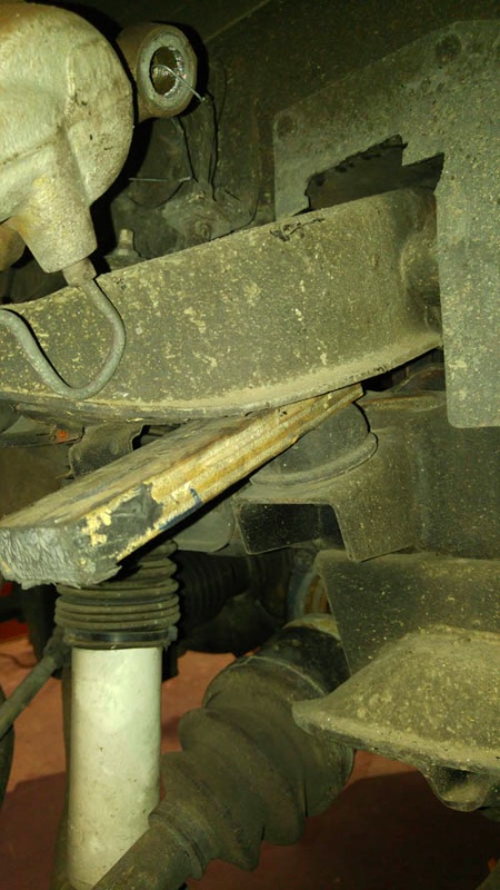 Wood block wedged against the upper control arm bump stop before jacking